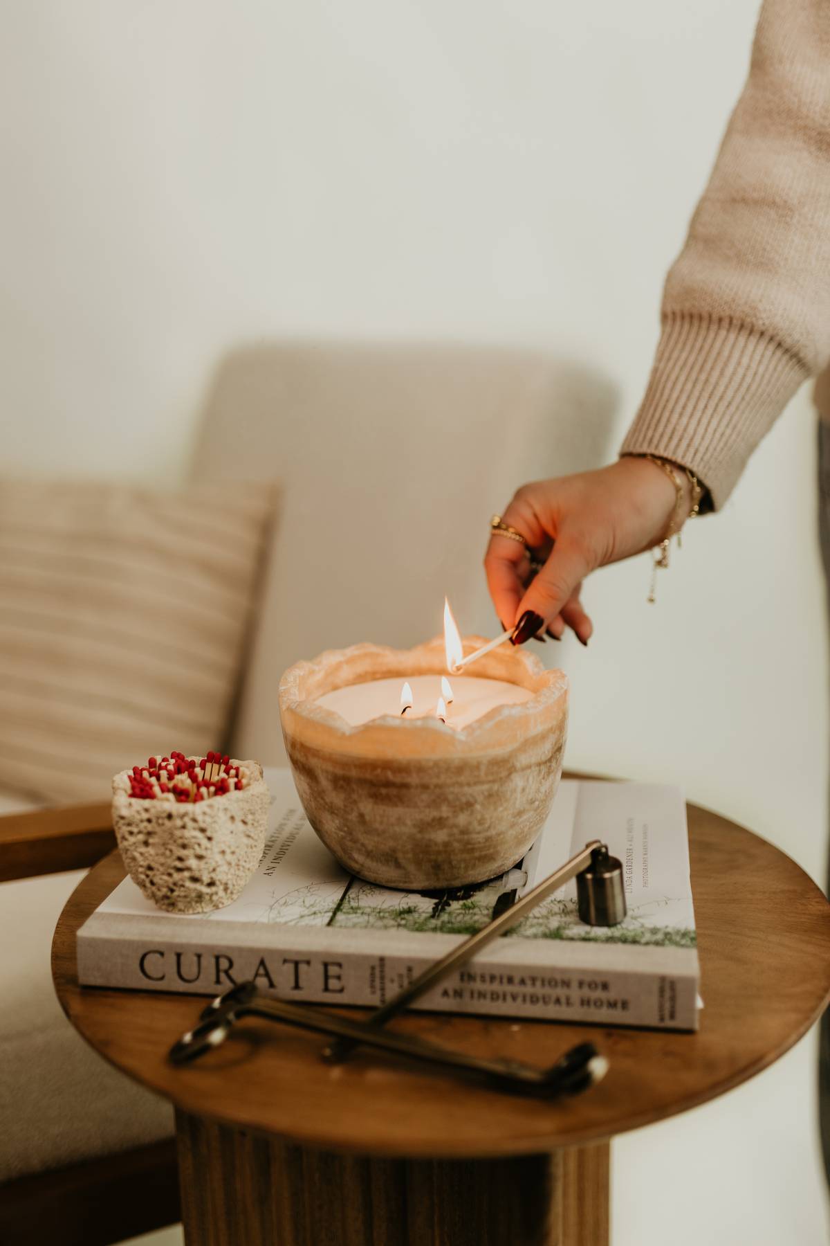 Person lighting the Travertine Candle Bowl, a reusable earthy stone bowl candle with unique veining, by Studio Hill Designs