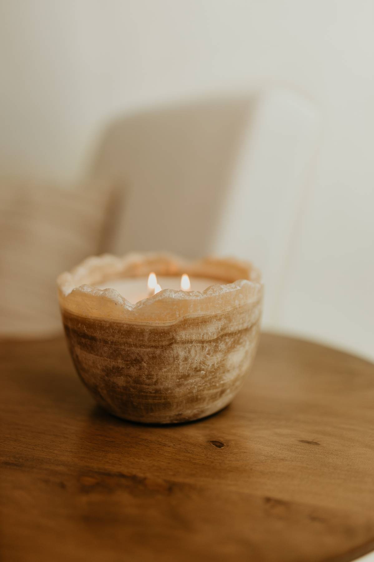 The Travertine Candle Bowl, a reusable stone bowl candle in earthy tones on a wooden surface.