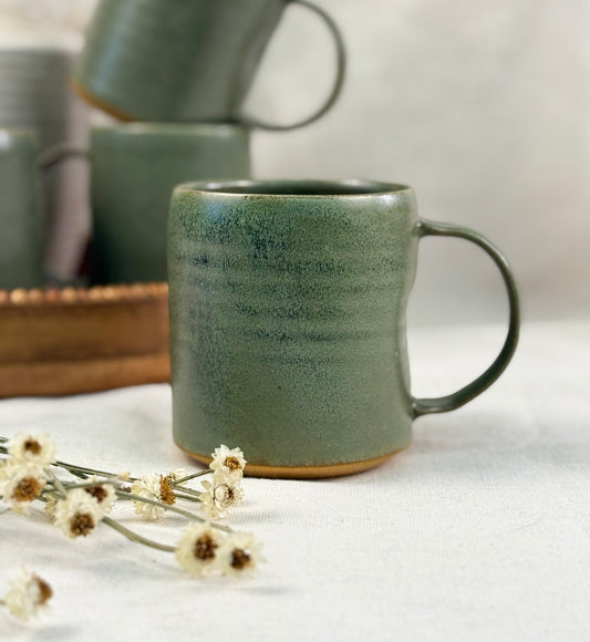 Handmade sage green ceramic mug styled with dried flowers on linen background curated by studio hill designs..