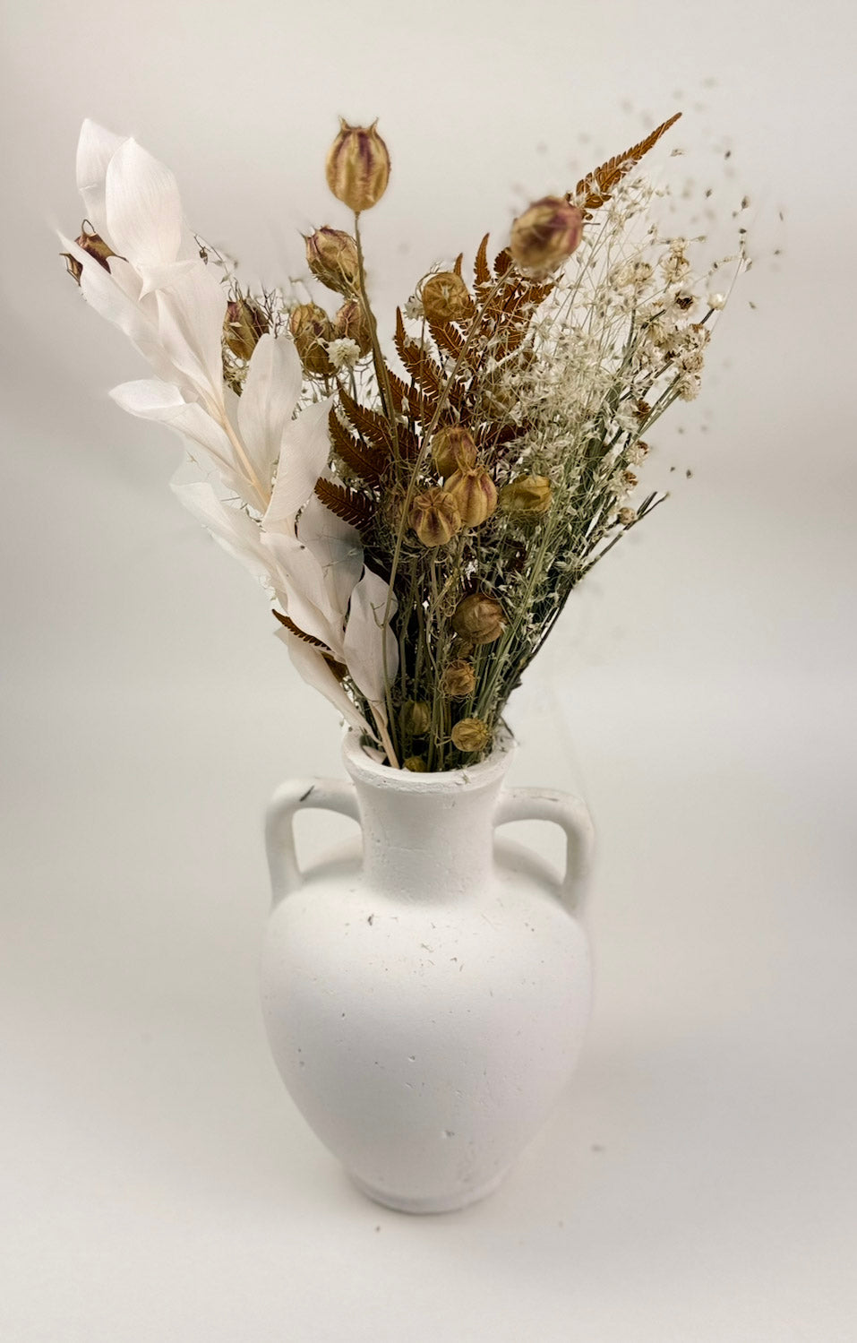 The Harvest Dried Floral Bouquet by Studio Hill Designs styled in white matte vase on with white background.