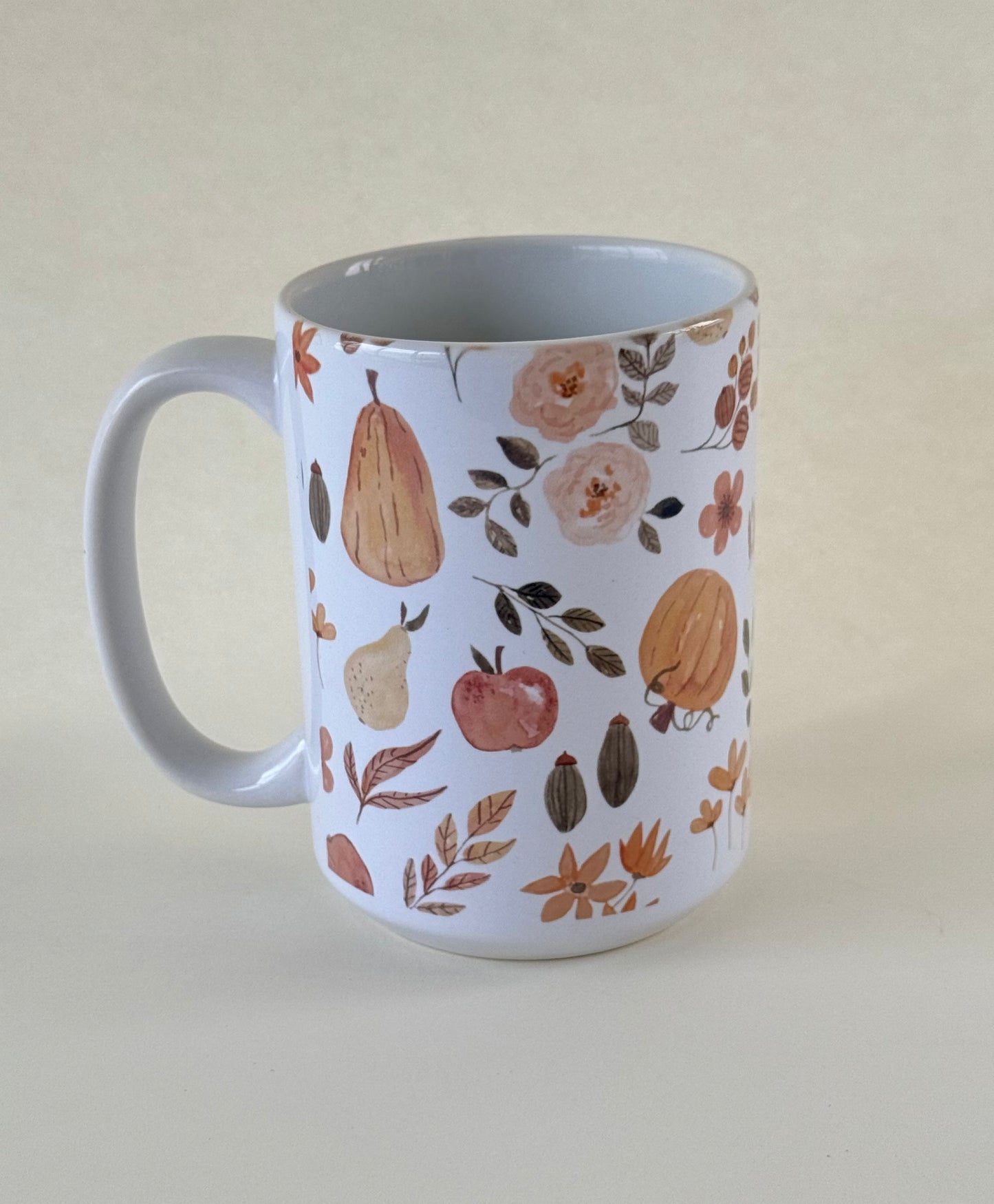The Autumn Edit  mug with autumn-themed design featuring pears, apples, and leaves on a beige background designed by studio hill designs.
