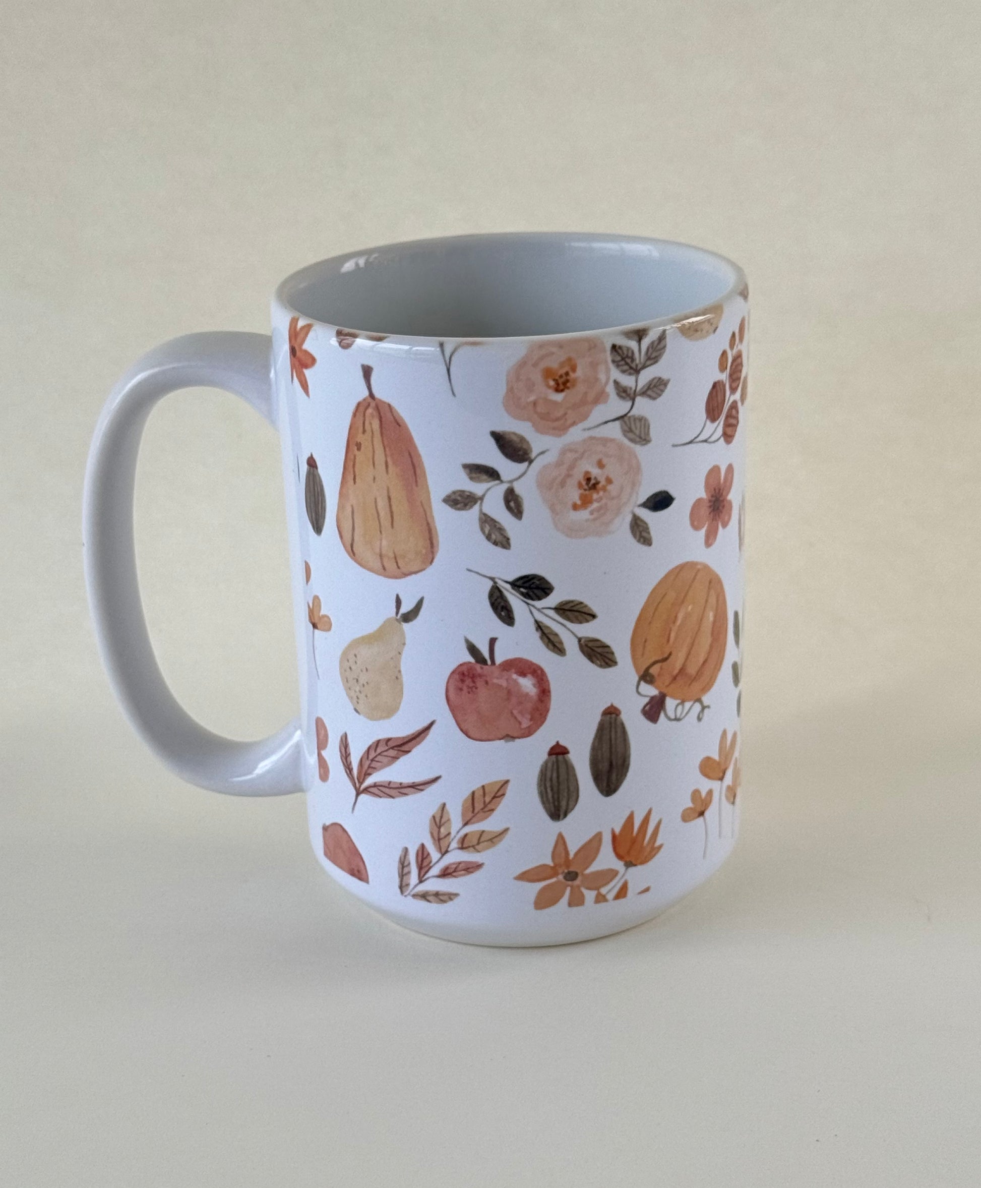 The Autumn Edit  mug with autumn-themed design featuring pears, apples, and leaves on a beige background designed by studio hill designs.