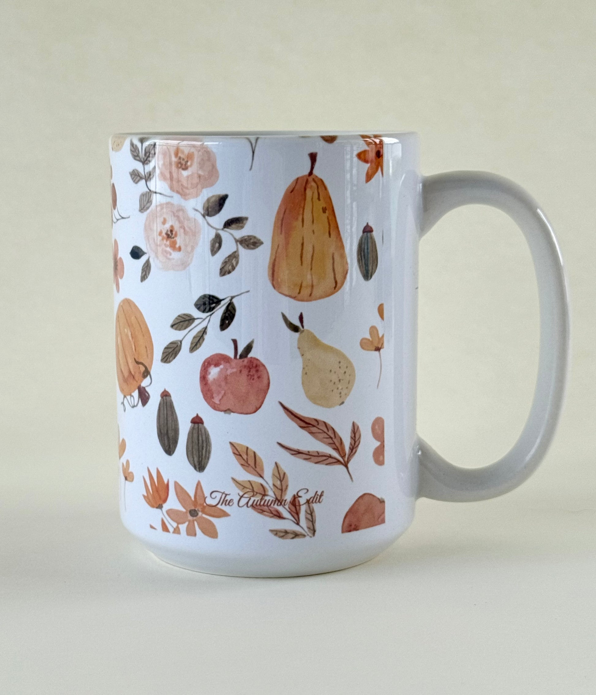The Autumn Edit  mug with autumn-themed design featuring pears, apples, and leaves on a beige background designed by studio hill designs.