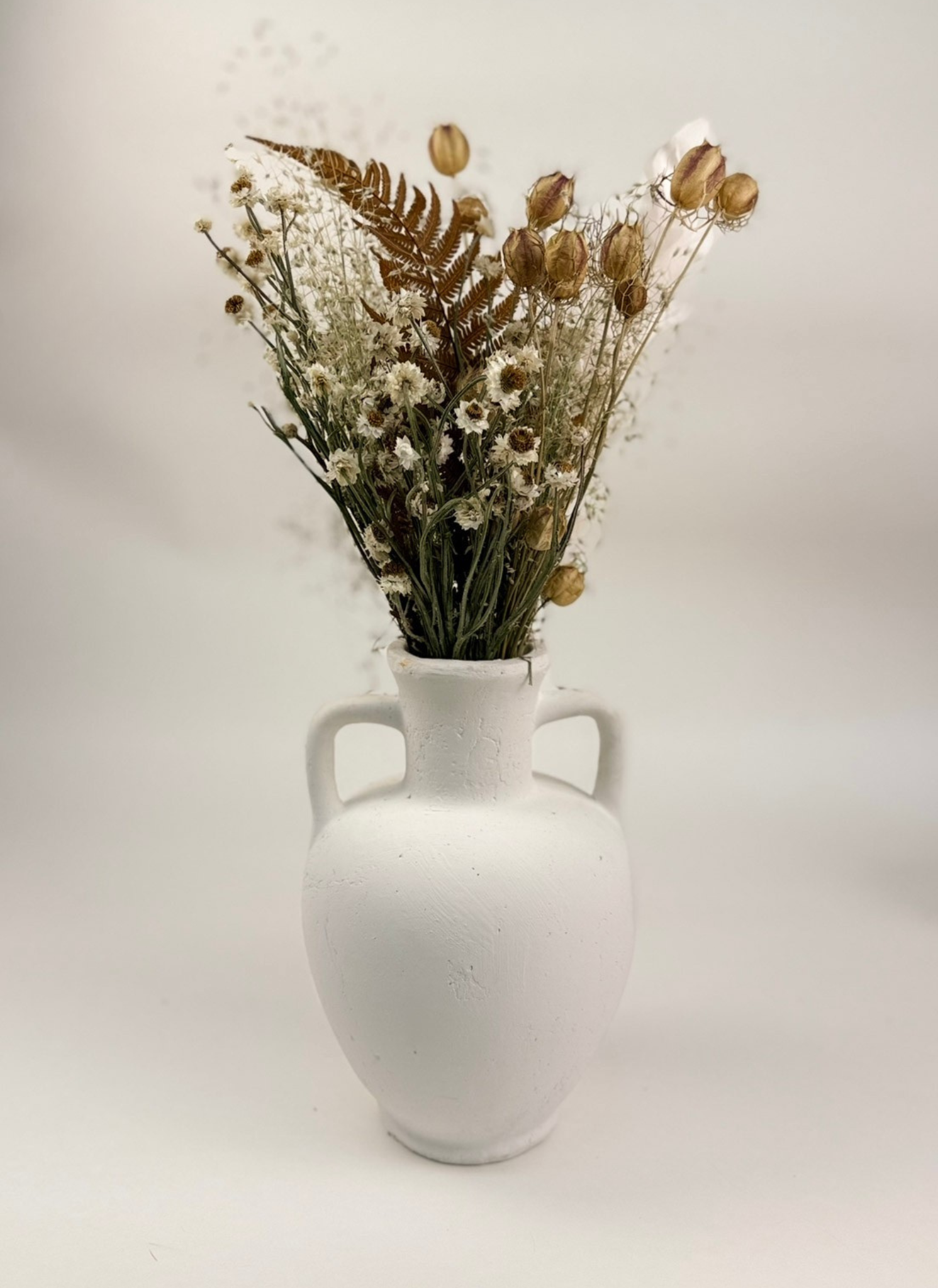 The Harvest Dried Floral Bouquet by Studio Hill Designs styled in white matte vase on with white background.