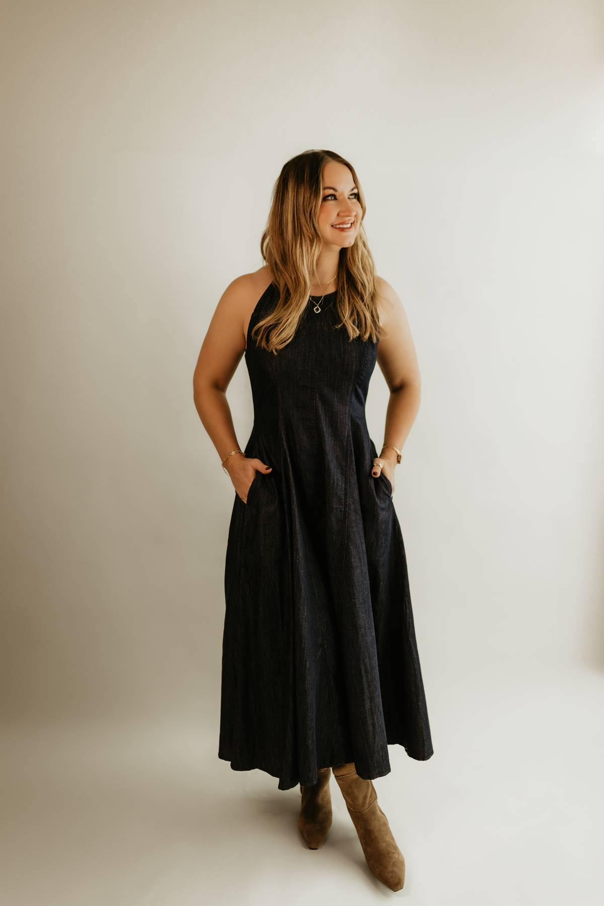 Woman wearing The Rowan Denim Midi Dress, a halter shaped, classic flowing dress with pockets, by Studio Hill Designs.