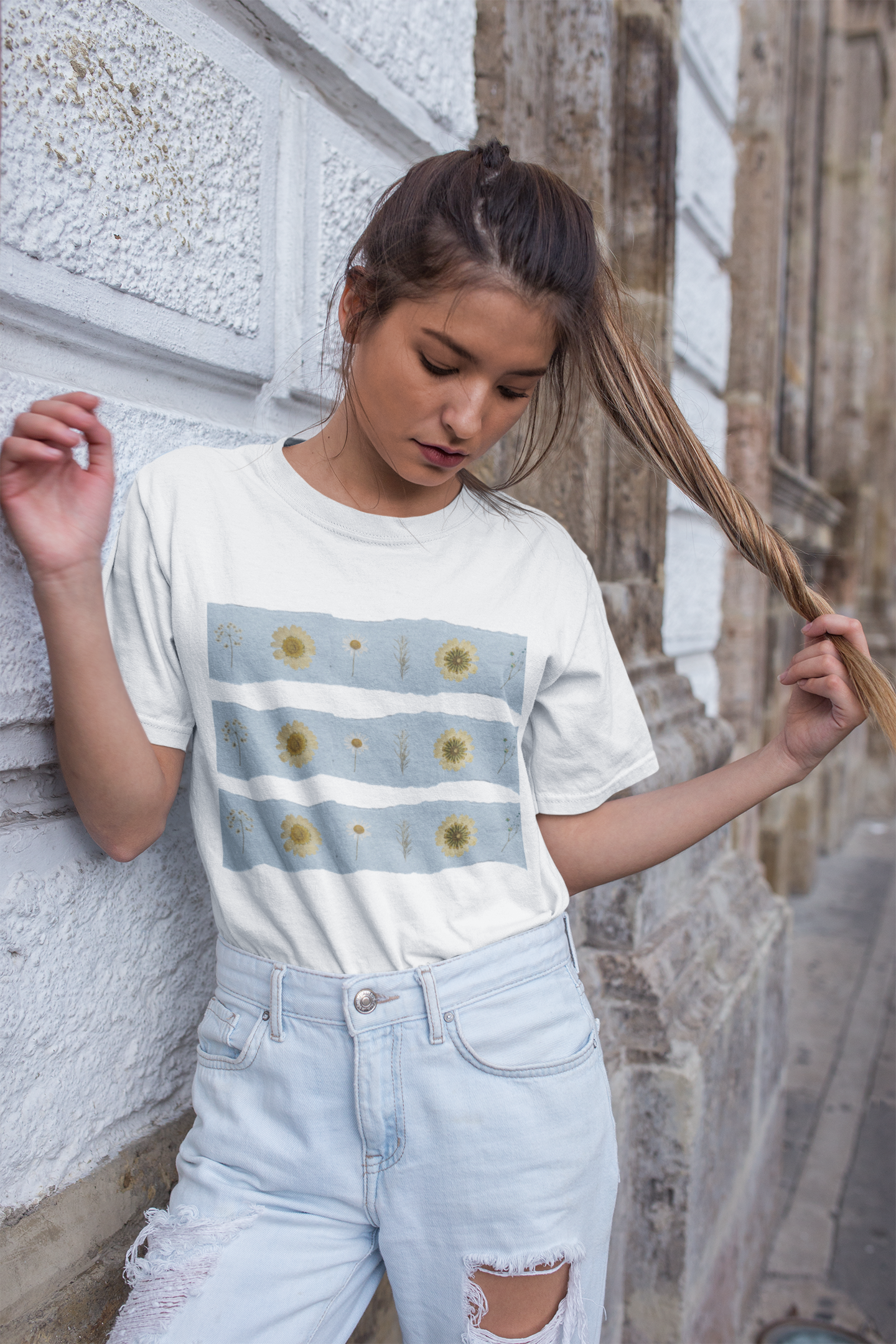Mockup of a woman wearing the white oversized wildflower graphic tee featuring blue stripes with rows of sunflowers and wildflowers by Studio Hill Designs 